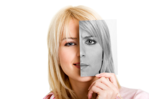 Woman holds photo to show two contrasting faces - one happy and colourful, the other serious and in black and white